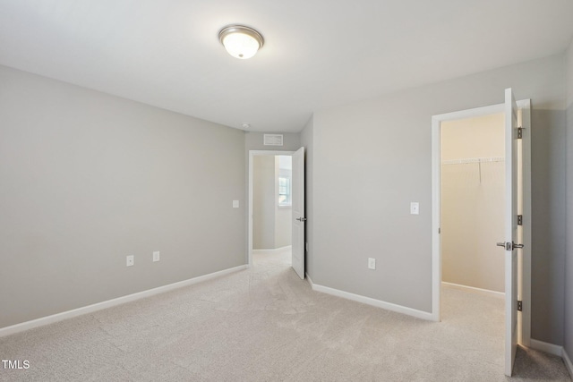 unfurnished bedroom featuring baseboards, light carpet, visible vents, and a spacious closet