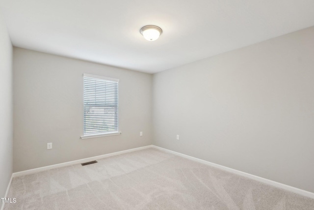 empty room featuring visible vents, light carpet, and baseboards