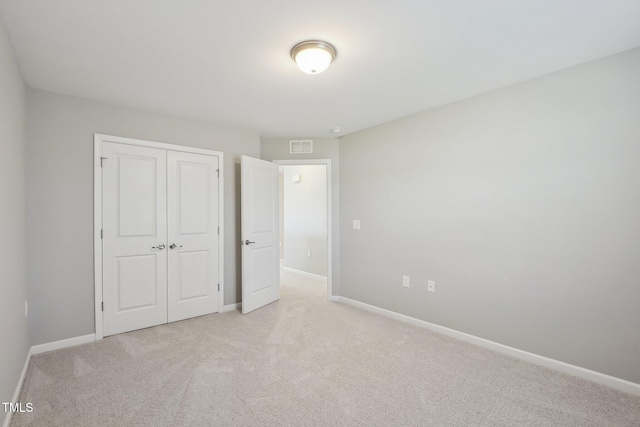 unfurnished bedroom featuring light carpet, baseboards, and a closet