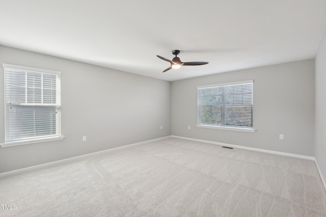 empty room featuring baseboards, visible vents, carpet floors, and ceiling fan