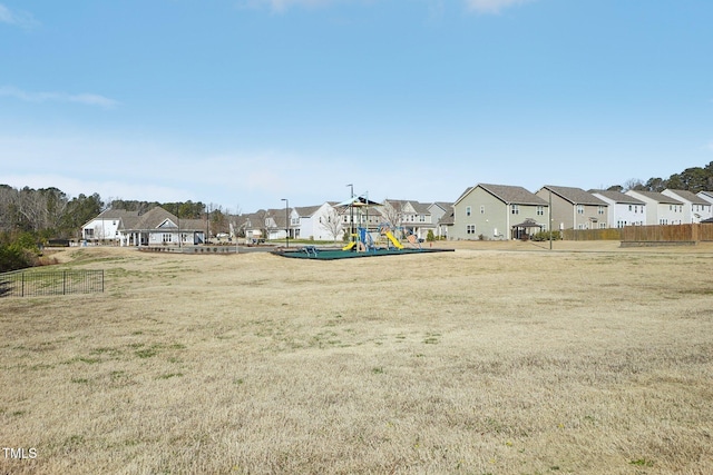 community play area featuring a residential view, a lawn, and fence