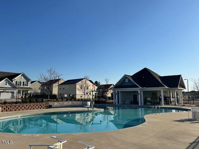 community pool with a patio, fence, and a residential view