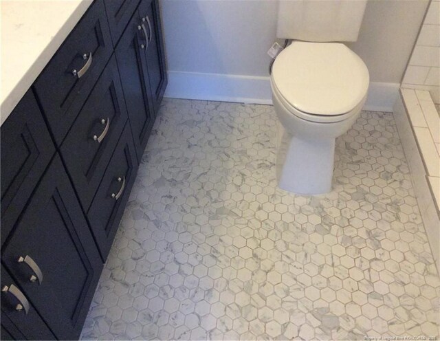 bathroom with baseboards, toilet, and vanity