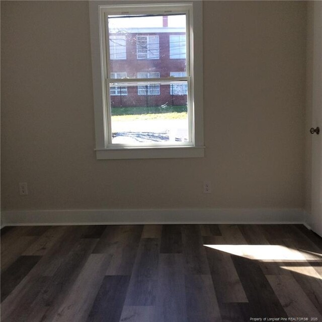 spare room featuring baseboards and dark wood-style flooring