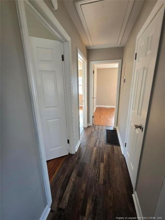 hallway featuring visible vents, baseboards, attic access, and wood finished floors