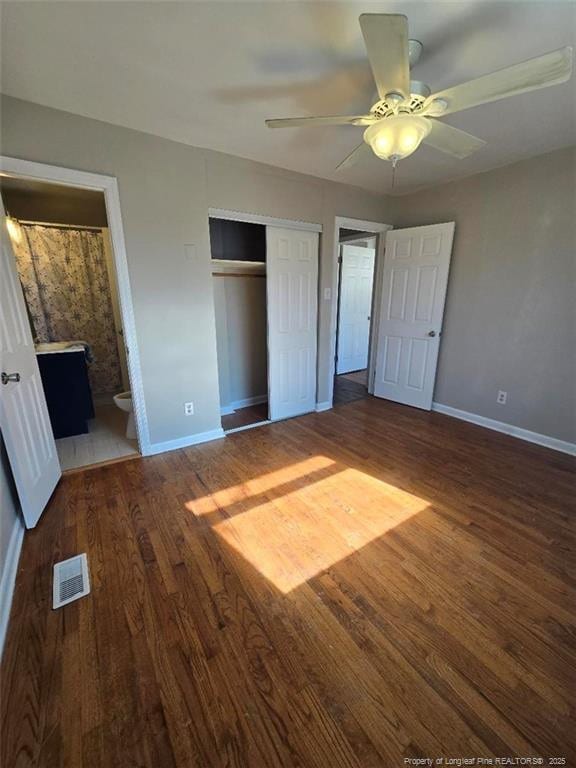 unfurnished bedroom featuring a closet, visible vents, baseboards, and wood finished floors