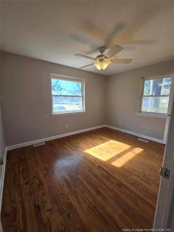 unfurnished room featuring visible vents, baseboards, and dark wood-style flooring