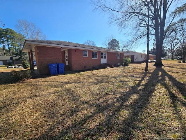 rear view of house featuring crawl space, a lawn, and brick siding