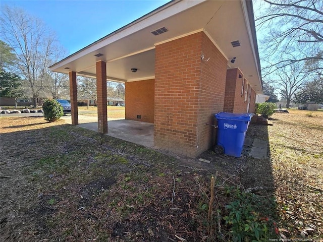 exterior space with crawl space, brick siding, and a carport