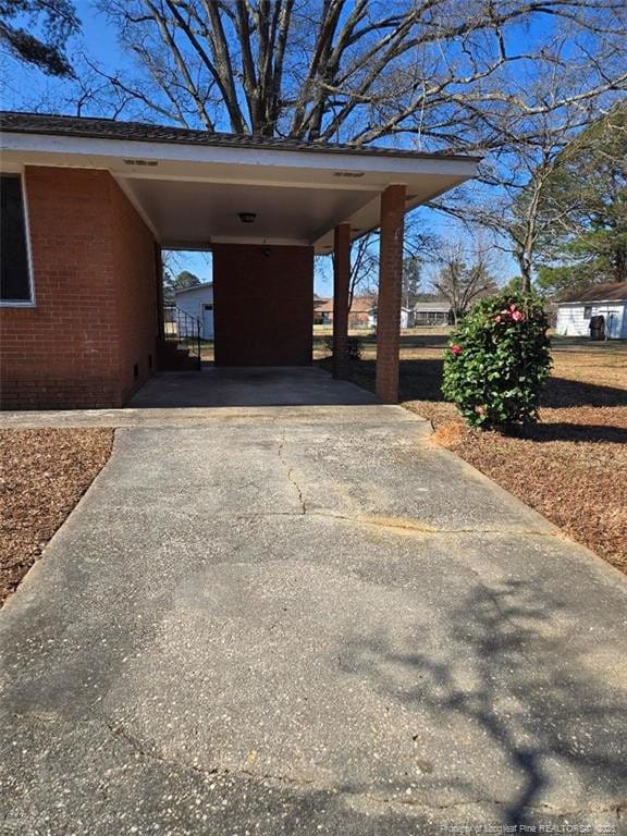 view of parking / parking lot with a carport and concrete driveway