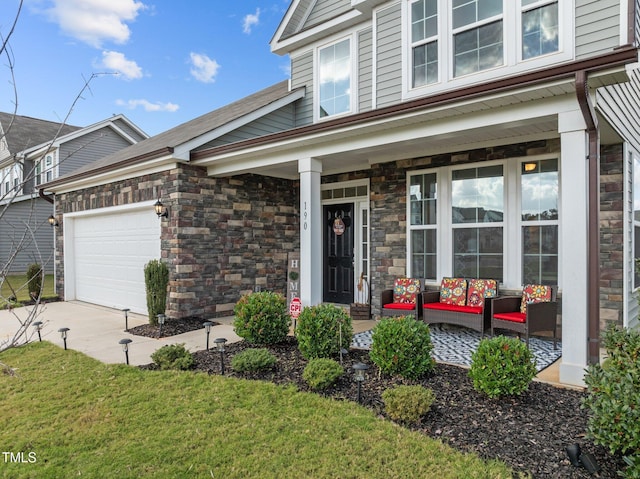 view of front of house featuring a porch, stone siding, a garage, and driveway