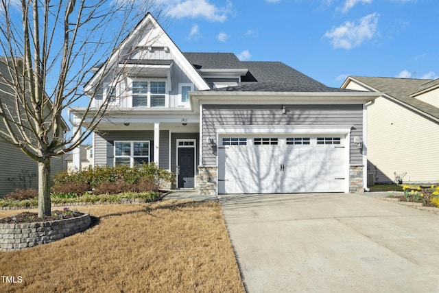 view of front facade featuring board and batten siding, roof with shingles, a garage, stone siding, and driveway