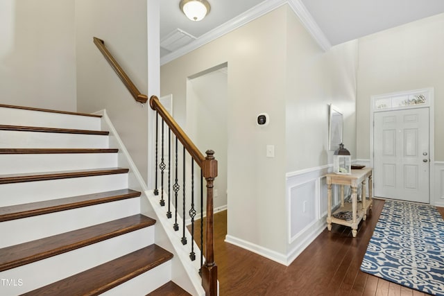 staircase featuring a decorative wall, a wainscoted wall, crown molding, and wood finished floors