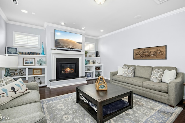 living area featuring wood finished floors, baseboards, recessed lighting, ornamental molding, and a glass covered fireplace