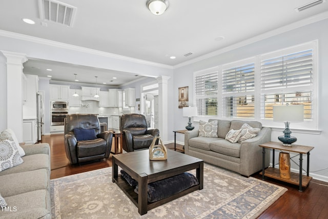 living area with visible vents, dark wood-type flooring, crown molding, and ornate columns