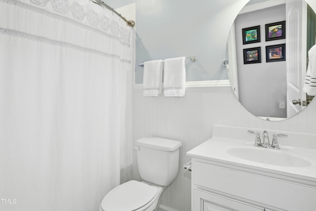 full bath with vanity, toilet, and a wainscoted wall