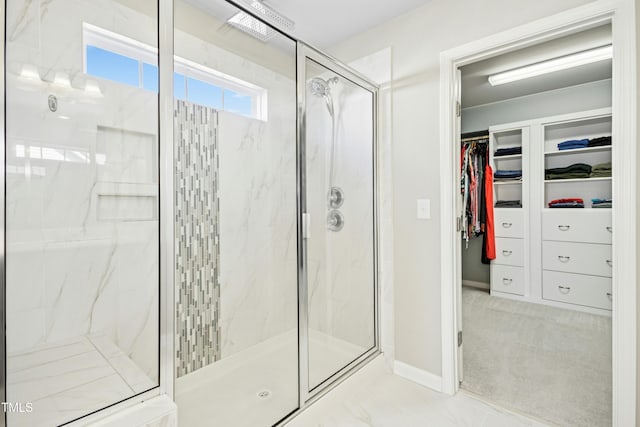 bathroom featuring a marble finish shower, baseboards, and a walk in closet