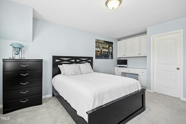 bedroom with light carpet, baseboards, and built in study area