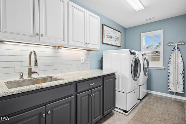 washroom with visible vents, a sink, washer and dryer, cabinet space, and light tile patterned floors