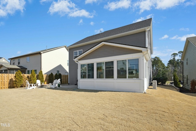 back of house with fence, a lawn, and an outdoor fire pit