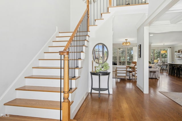 stairs with a high ceiling, baseboards, and wood finished floors