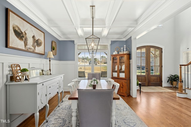 dining area featuring beamed ceiling, coffered ceiling, wood finished floors, french doors, and arched walkways