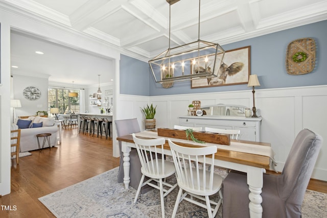 dining space featuring crown molding, a chandelier, beam ceiling, wood finished floors, and coffered ceiling