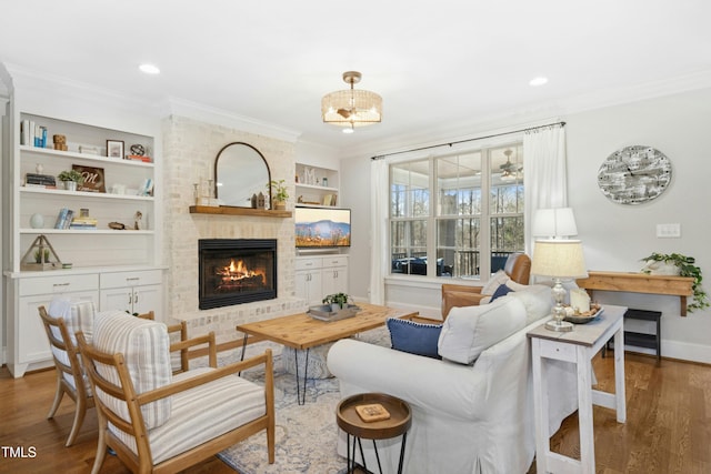 living room featuring a brick fireplace, wood finished floors, baseboards, and ornamental molding