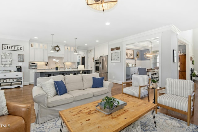 living room with crown molding, recessed lighting, wood finished floors, and a chandelier