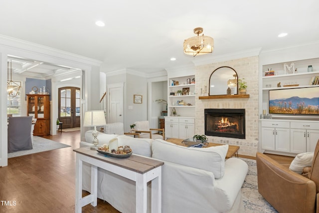 living room featuring built in features, wood finished floors, french doors, an inviting chandelier, and crown molding