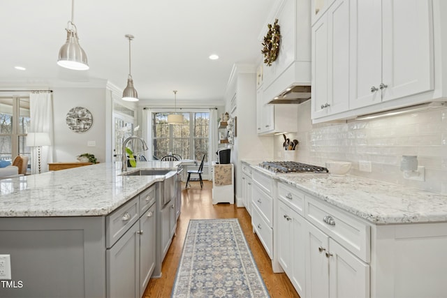 kitchen with custom exhaust hood, gray cabinets, ornamental molding, stainless steel gas stovetop, and tasteful backsplash