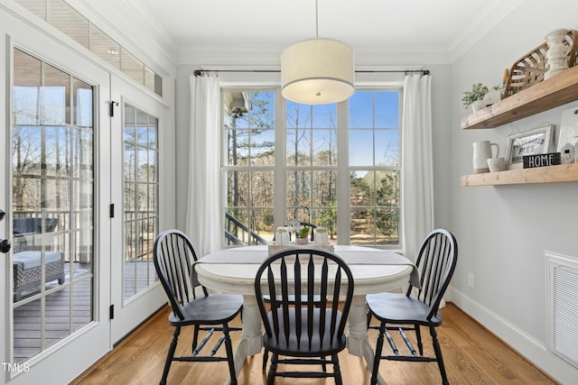 dining space featuring visible vents, baseboards, crown molding, and light wood-style floors