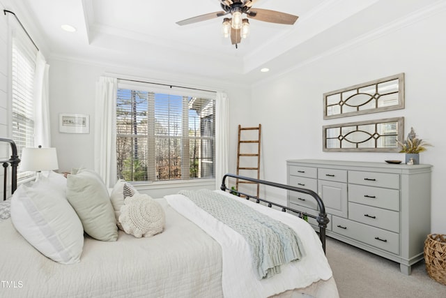 bedroom with a tray ceiling, recessed lighting, ceiling fan, crown molding, and light colored carpet