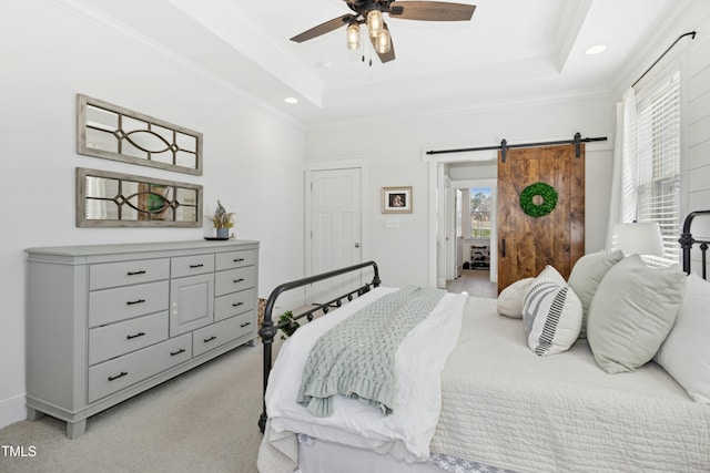 bedroom featuring a barn door, a raised ceiling, light carpet, and ornamental molding