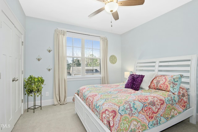 bedroom featuring light colored carpet, a ceiling fan, and baseboards