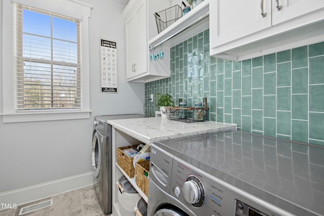 laundry area with baseboards, cabinet space, visible vents, and washing machine and clothes dryer