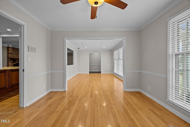 interior space featuring a stone fireplace, light wood-type flooring, baseboards, and ornamental molding