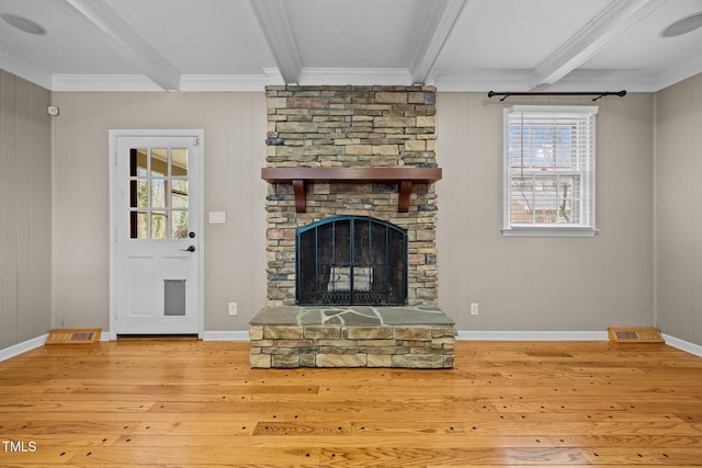 unfurnished living room featuring a stone fireplace, beam ceiling, a healthy amount of sunlight, and hardwood / wood-style floors