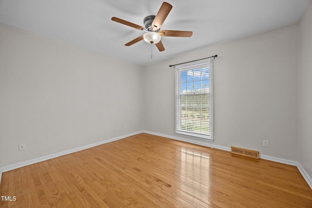 unfurnished room with hardwood / wood-style floors, baseboards, visible vents, and a ceiling fan