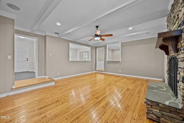 unfurnished living room with beam ceiling, light wood-style flooring, ornamental molding, a fireplace, and baseboards