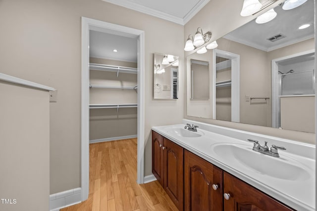 bathroom with visible vents, ornamental molding, wood finished floors, and a sink