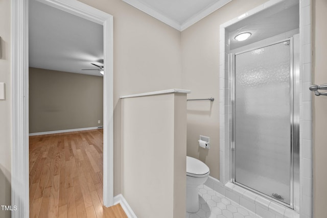 bathroom with crown molding, toilet, a ceiling fan, and a stall shower