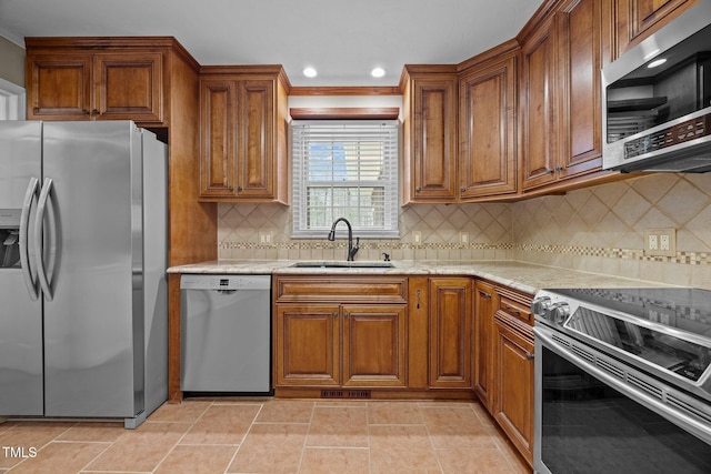 kitchen with light stone counters, brown cabinetry, visible vents, a sink, and stainless steel appliances