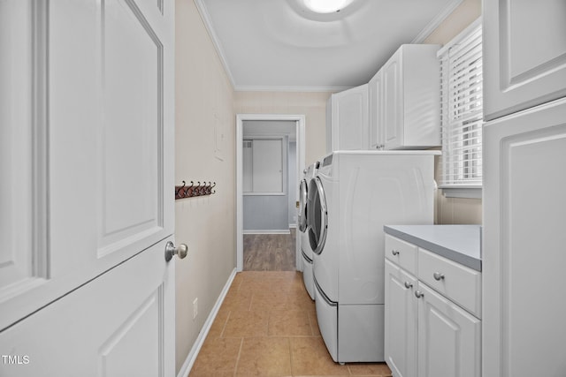 clothes washing area featuring baseboards, washing machine and clothes dryer, light tile patterned flooring, cabinet space, and ornamental molding