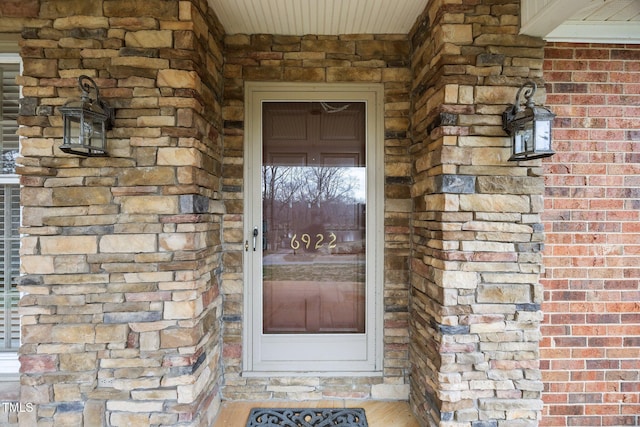 entrance to property featuring stone siding and brick siding