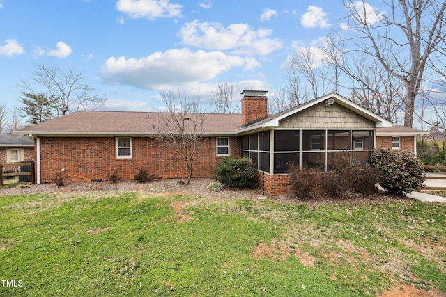 back of property featuring a yard, brick siding, a chimney, and a sunroom