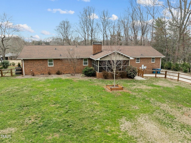 rear view of property with brick siding, a lawn, a chimney, and a fenced backyard