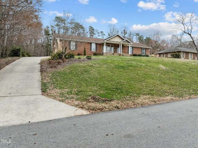 ranch-style house with a front yard, a porch, brick siding, and concrete driveway