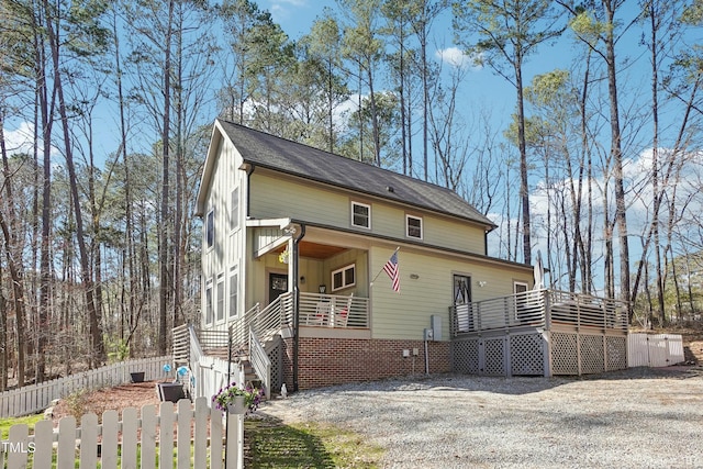 view of front facade featuring a fenced front yard, board and batten siding, a deck, and stairs