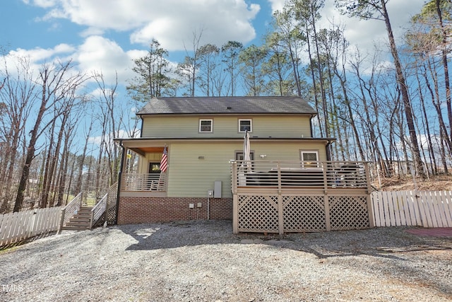 rear view of house featuring a deck, fence, and crawl space